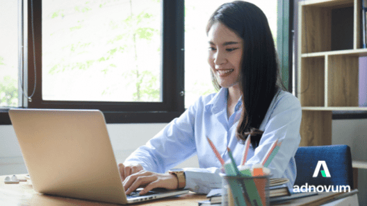 Young woman sitting at desk typing on laptop and smiling 