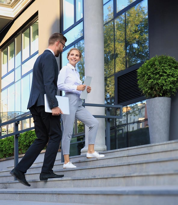 Zwei Personen laufen eine Treppe hoch in ein Bürogebäude