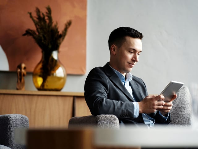 Man sitting on a chair in an office and looking at a tablets' screen