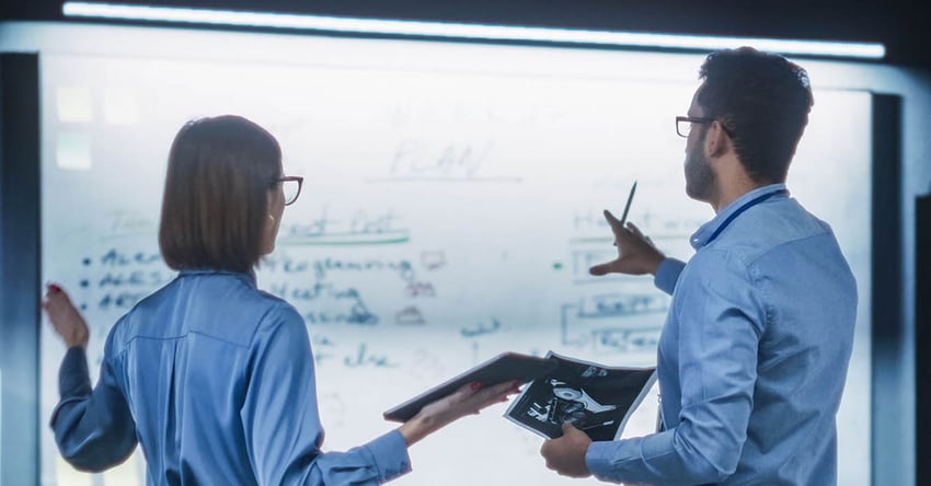 business man and woman are planning together in front of whiteboard