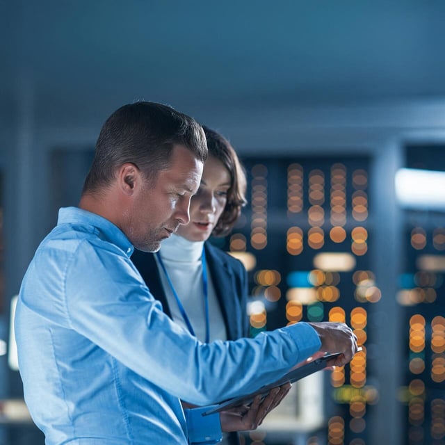 Zwei Mitarbeitende, die in einem Serverraum an einem Tablet arbeiten