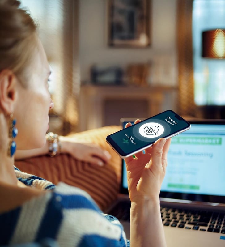 Frau, die per Smartphone mit einem Kundenservice-Voicebot spricht