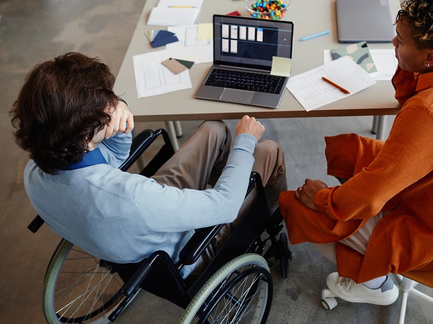 man in wheelchair meeting with a woman at a table