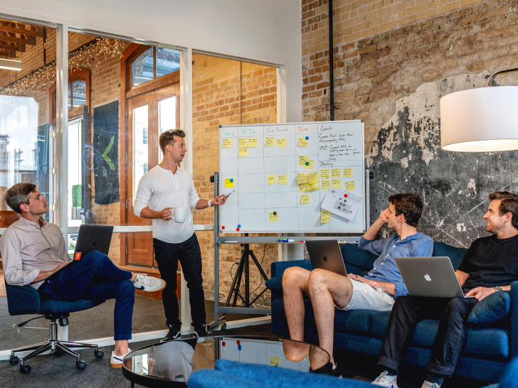 Kollegen sitzen um ein Whiteboard und diskutieren