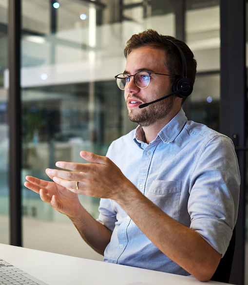Mitarbeitender eines Service Center, der an einem Schreibtisch sitzt und über ein Headset telefoniert