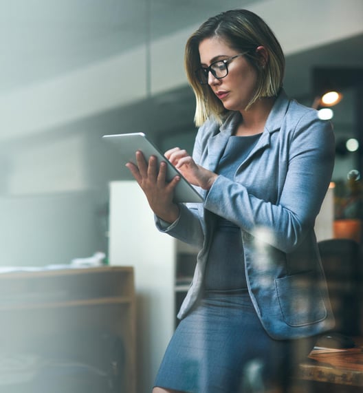 A woman leaning on a desk and working with a tablet