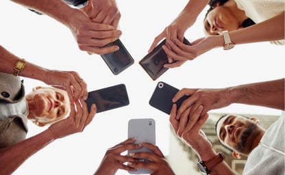 Five people in a circle presenting their smartphones to the camera
