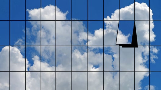 Fassade eines Hochhauses, die eine Wolke im Himmel widerspiegelt