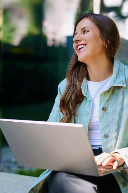 Frau arbeitet an einem Laptop und lächelt