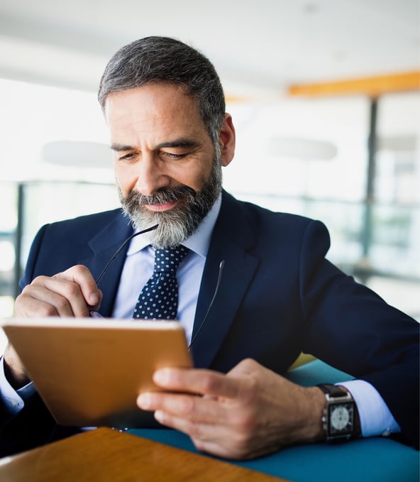 Sitting man in suit writes on tablet and smiles 