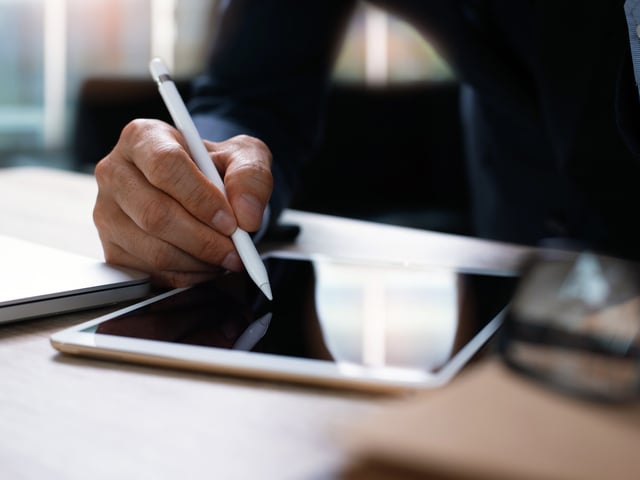 Mann schreibt mit Stift auf Tablet 