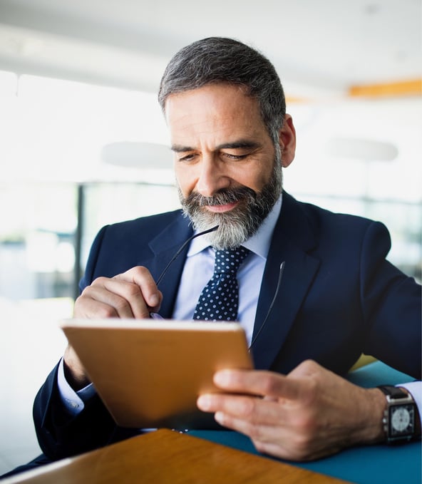 Sitting man in suit writes on tablet and smiles 