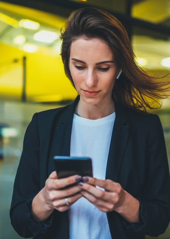 Woman in business suit looking at smartphone in her hands 