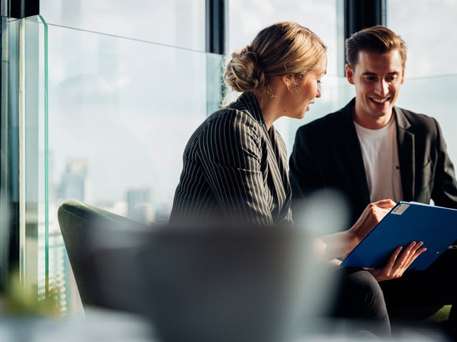 Female and male working colleagues smiling and looking at book 