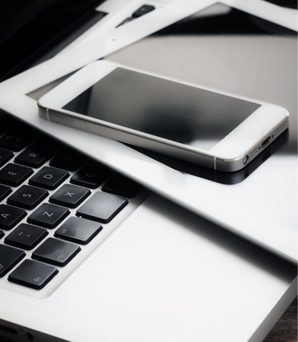 Smartphone and tablet lying on laptop keyboard 