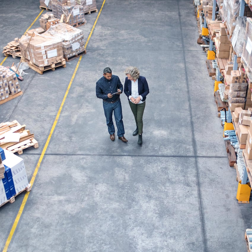 Male and female working colleagues in a storehouse looking at screen 