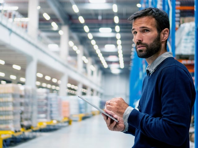 Man holding tablet in his hand looking at storehouse items 