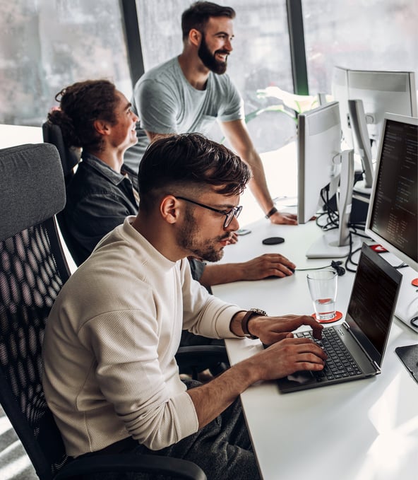 Male and female working colleagues look at computer screen and smile 