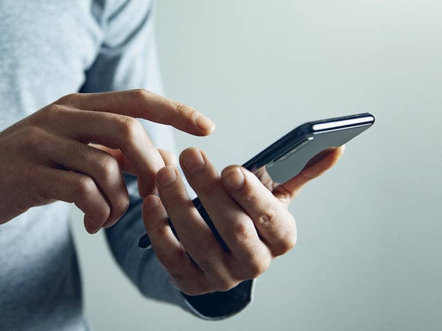 Partial lateral view of person holding a smartphone 