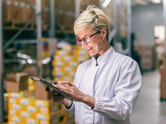 Frau in Lagerhalle arbeitet an ihrem Tablet  