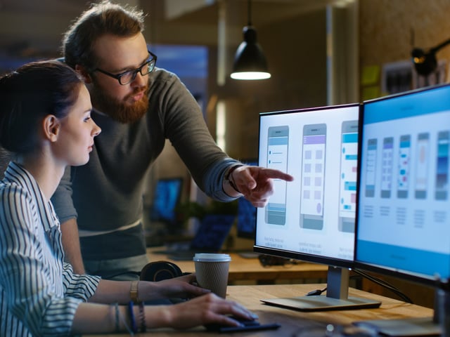 Male and female working colleagues look at computer screen