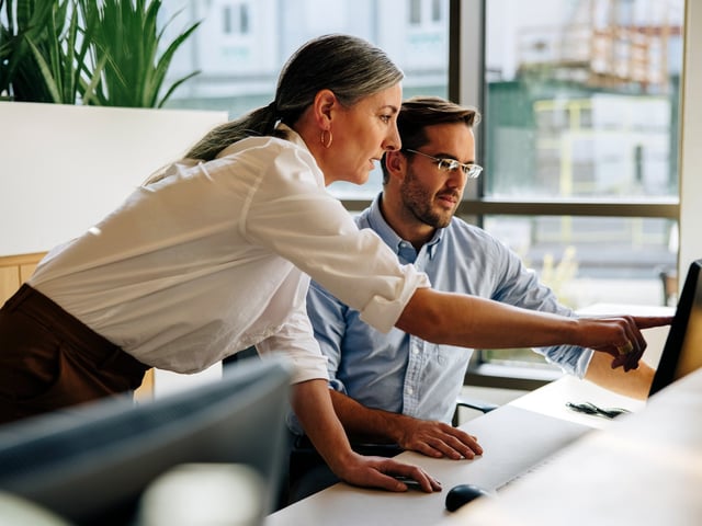 Female working colleague shows something on the computer screen to male colleague 