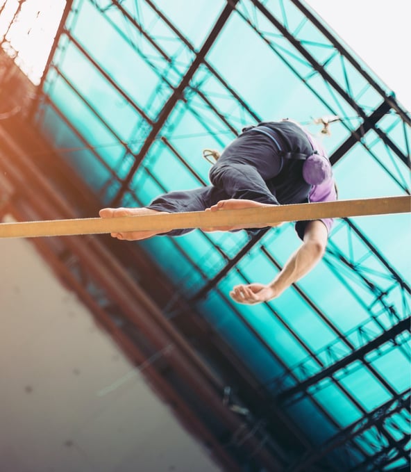 Man balancing over fine wooden rail, seen from below 