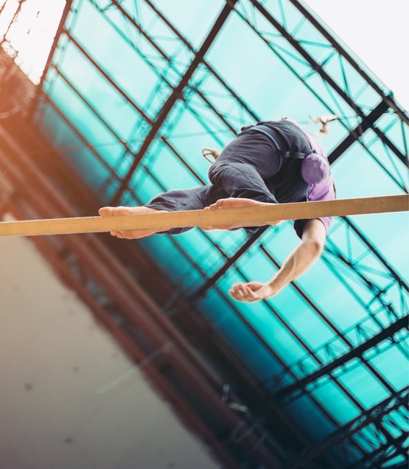 Man balancing over fine wooden rail, seen from below 