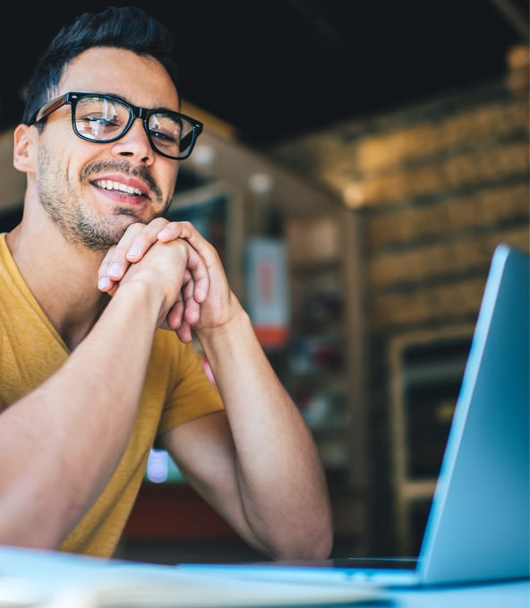 Man sits behind laptop and smiles 