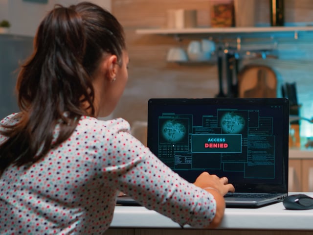 Woman working on dark laptop display, seen from behind  