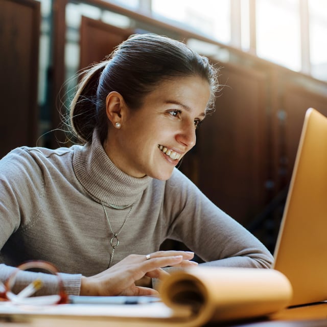 Woman in front of laptop, smiling 