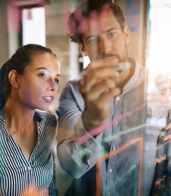 Female and male working colleagues writing on glass wall 