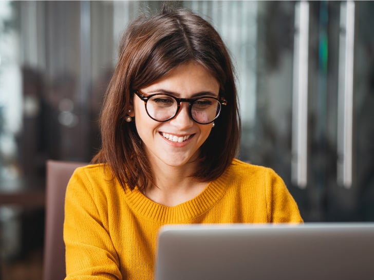 Woman sitting in front of laptop, smiling