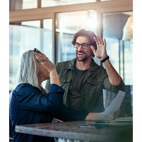 Female and male working colleagues about to give each other high five 