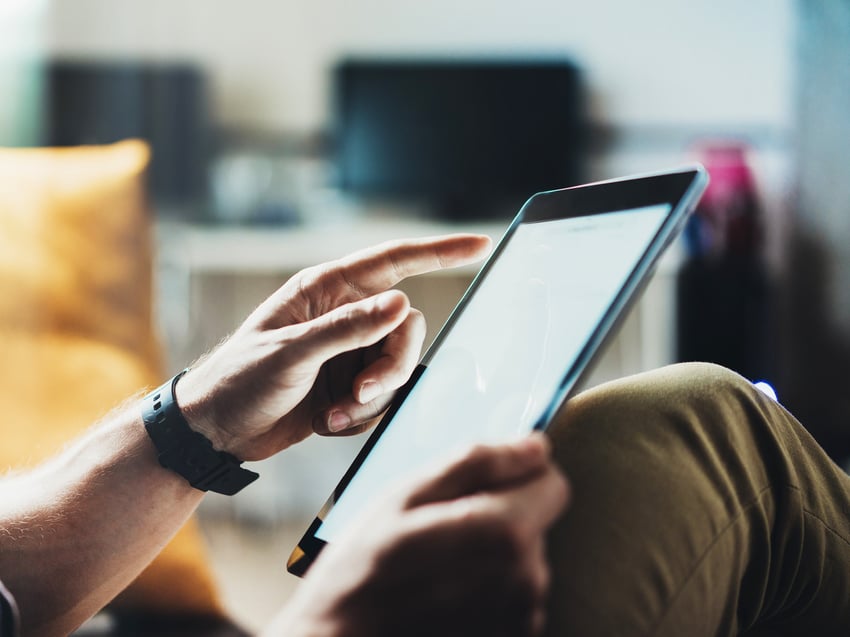 Person holding pen pointing at tablet screen 