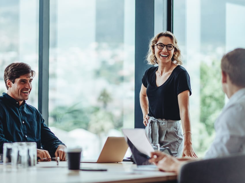 Three working colleagues smiling in meeting room  