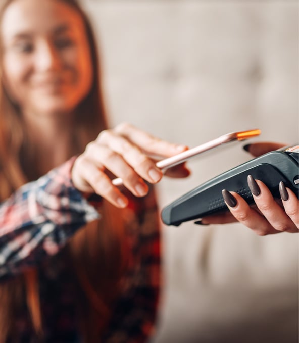 Woman holding smartphone to payment terminal 