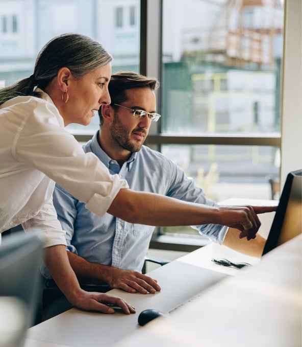 Female working colleague shows something on the computer screen to male colleague 