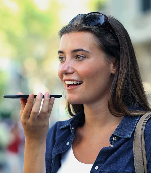 Lateral view of young woman talking on smartphone in hands, smiling 