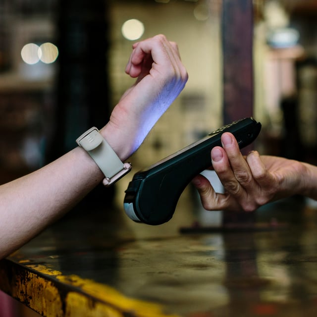 Frau hält Smartwatch an Bezahlterminal 