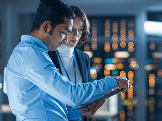 Male and female working colleagues studying tablet in server room 