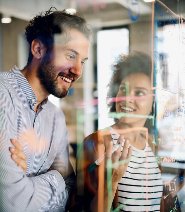 Male and female colleague talking seen through glass wall 