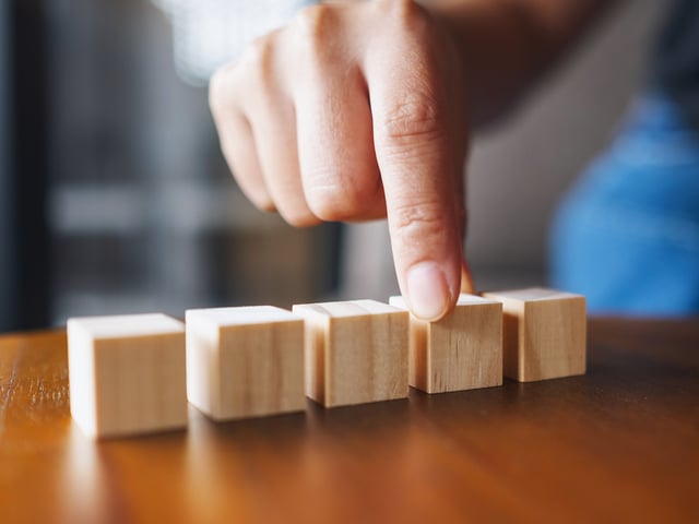 Hand ordnet kleine Holzklötzchen 