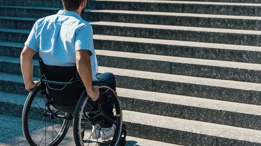 Man in wheelchair at bottom of stairs 