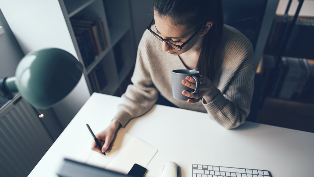 Woman behind laptop taking notes 