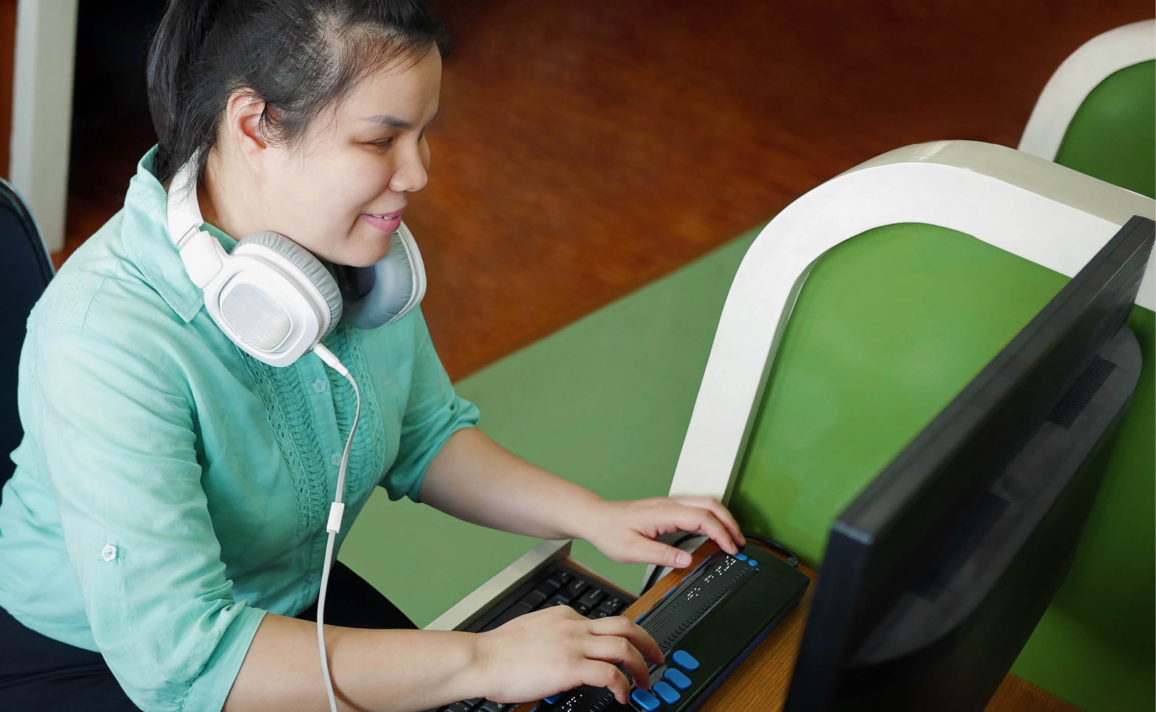 visually impaired person using special keyboard with her computer