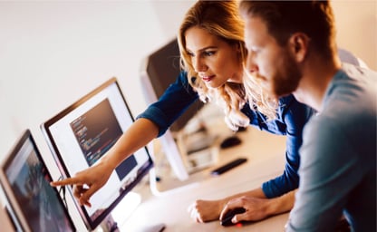 Female and male working colleagues smiling and looking at a laptop screen 