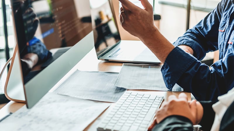 Männlicher Arbeitskollege zeigt auf den Computerbildschirm