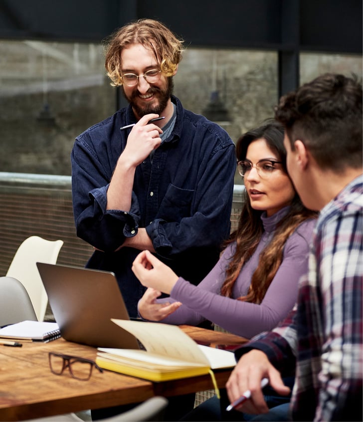 Female and male working colleagues smiling and looking at a laptop screen 