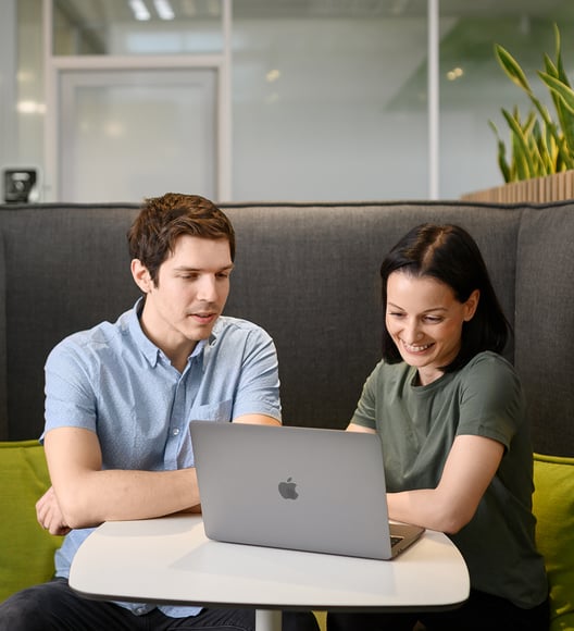 Man and woman sitting next to each other, smiling and looking at the laptop screen